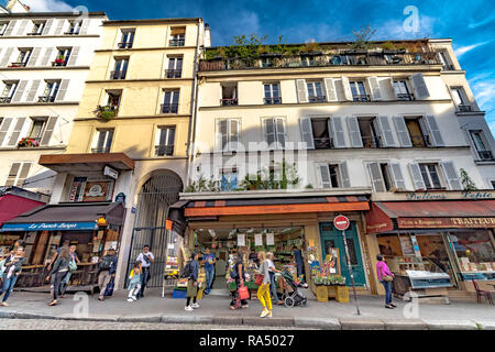 La gente camminare passato negozi ed appartamenti con persiane alle finestre ,nel tardo pomeriggio di sole estivo, Rue Lepic , Montmartre , Parigi Foto Stock