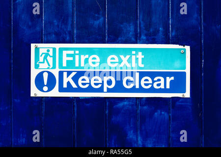 Fire exit mantenere chiaro segno sulla porta blu Foto Stock