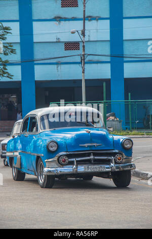 Classica auto d'epoca chevrolet blu che guida su una strada di fronte a un edificio blu, design automobilistico retrò e stile Havana, Cuba, Caraibi Foto Stock
