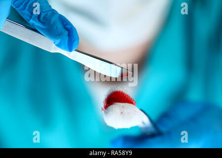 Medico chirurgo in sterili bracci uniforme tenendo gli utensili con materiale bio Foto Stock