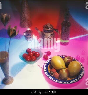 Ancora la vita di frutta , una teiera, un vaso di fiori con uno sfondo colorato Foto Stock