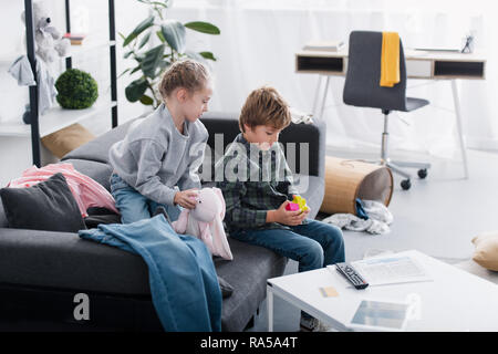 Angolo di alta vista dei fratelli seduti sul divano e giocare con i giocattoli a casa Foto Stock
