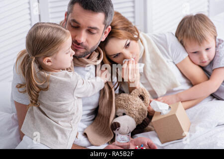 Adorabili e sorella e fratello abbraccia i genitori malati in camera da letto Foto Stock