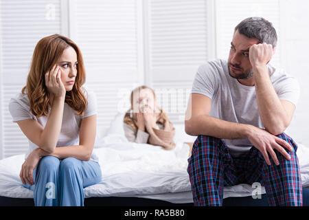 Preoccupati i genitori seduti vicino al malato la figlia in camera da letto e guardando ogni altro Foto Stock