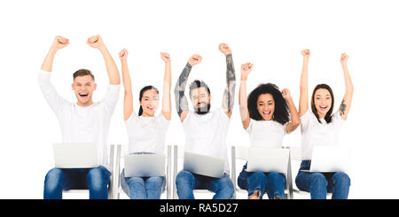 Gruppo multietnico di persone che utilizzano i computer portatili e di gioia con le mani sopra la testa isolata su bianco Foto Stock