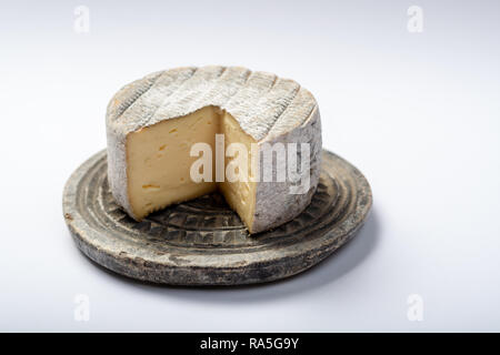 Round coppia francese di formaggio tomme con un pezzo tagliato sulla pietra grigia piastra isolata da vicino Foto Stock