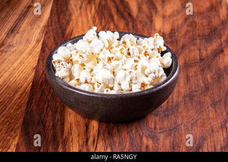 Popcorn sale sul tavolo di legno. Il Popcorn in una ciotola di pietra. La visione di un filmato con popcorn. Copia dello spazio. Pop corn. Foto Stock