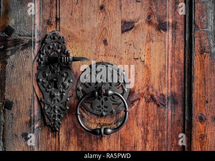 Forgiato la maniglia della porta e respingente su una vecchia porta di legno, Austria Foto Stock