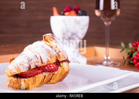 Stile Francese romantico picnic estivo impostazione. Flat-lay di bicchieri di vino rosato, fragole fresche, croissant, formaggio brie, cappello, occhiali da sole, peonia flo Foto Stock