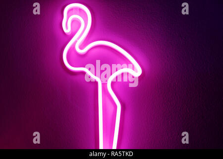 Fenicottero rosa neon di luce sulla parete. Illuminata figura decorativa di incandescente flamingo forma segno decorazione di una parete. Foto Stock