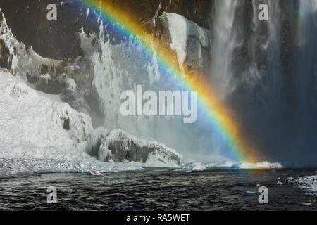 Skógafoss, una bellissima cascata con un arcobaleno in spray, lungo il fiume Skógá e caduta ex scogliere sul mare, lungo la costa sud dell'Islanda i Foto Stock