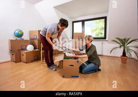 Coppia giovane in una stanza vuota in un nuovo appartamento di disimballare le prime scatole Foto Stock