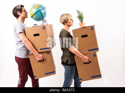 Coppia giovane che trasportano contenitori per il trasloco, un mondo e una pianta di casa Foto Stock