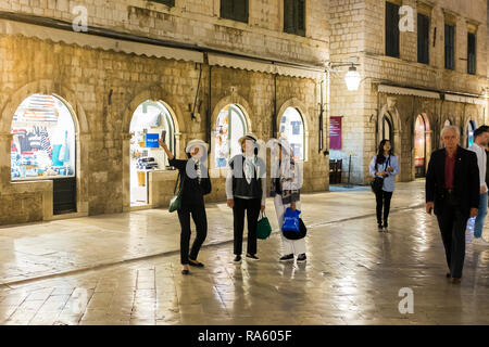 Un gruppo di turisti asiatici prendono un selfie con uno smartphone sulla Stradun, una strada pedonale principale nella città murata di Dubrovnik, Croazia. Foto Stock