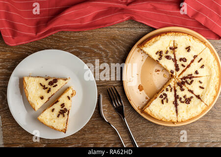 In casa la cheesecake cosparso con scaglie di cioccolato su uno sfondo di legno. Vista superiore Foto Stock