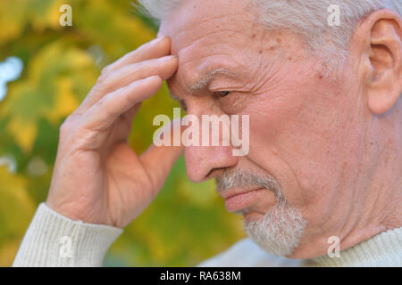 Riflessivo senior uomo su blured autunno sfondo della foresta Foto Stock