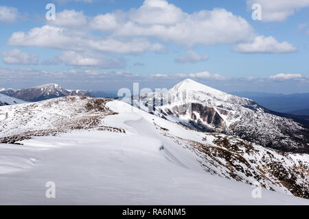 Vista delle colline pietrose con la neve e il blu del cielo. Molla di drammatica scena. Fotografia di paesaggi Foto Stock