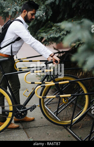 Business, lifestyle, trasporto e concetto di persone - giovani indiani uomo bicicletta parcheggio su strada di città Foto Stock
