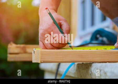 Carpenter utilizzando le scrive una matita sulla trave di legno un nuovo home progetto constructiion Foto Stock