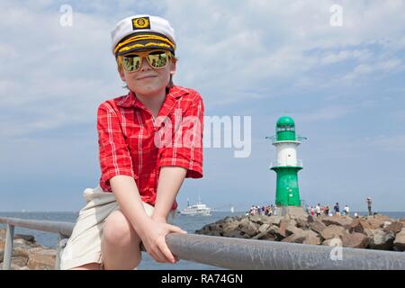 Ragazzo con un capitano del cappello, seduti nella parte anteriore del Faro di Warnemunde, Rostock, Meclemburgo-Pomerania Occidentale, Germania Foto Stock