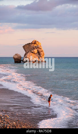 Paphos, Cipro - 24 Novembre 2018: un ragazzo suona presso la spiaggia di Petra tou Romiou rocce in Paphos, Cipro. La spiaggia è considerata essere Afrodite Foto Stock