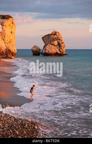 Paphos, Cipro - 24 Novembre 2018: un ragazzo suona presso la spiaggia di Petra tou Romiou rocce in Paphos, Cipro. La spiaggia è considerata essere Afrodite Foto Stock