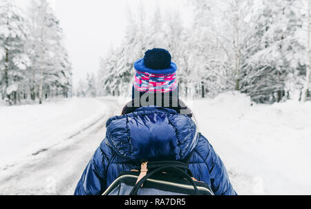 Lo stile di vita di viaggio. Giovane donna con zaino in inverno sulla strada innevata in Svezia Foto Stock