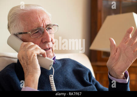 Senior uomo indesiderato di ricezione chiamata telefonica a casa Foto Stock