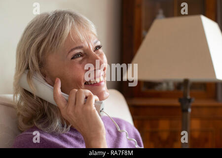 Sorridente donna Senior usando il telefono di casa Foto Stock