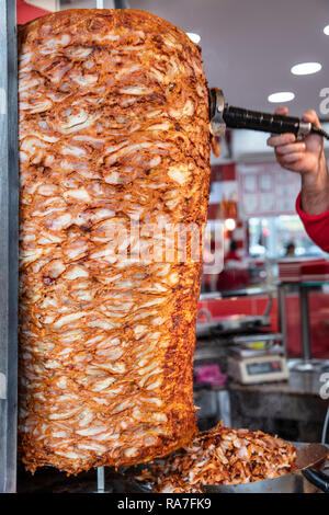 Deliziosi spiedini di fast food pollo shawarma döner cottura della carne e rotazione di fianco a fianco sullo spiedo rotante araba in Medio Orientale o in stile mediterraneo. Foto Stock