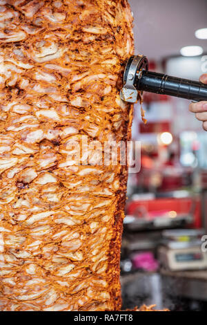 Deliziosi spiedini di fast food pollo shawarma döner cottura della carne e rotazione di fianco a fianco sullo spiedo rotante araba in Medio Orientale o in stile mediterraneo. Foto Stock