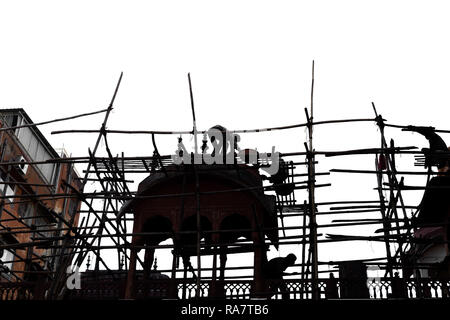 Silhouette Woker sulla impalcatura di bamboo lavorando sulla costruzione di costruzione sito. Foto Stock