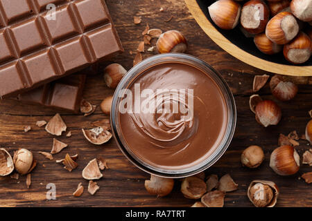 Cioccolato da spalmare con le nocciole su sfondo di legno Foto Stock