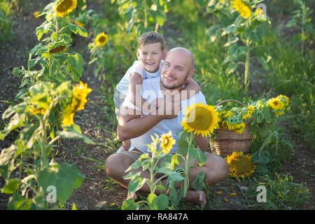 Papà con figlio abbracciando in un campo di girasoli. Figlio abbraccia il Padre in un campo di girasoli Foto Stock