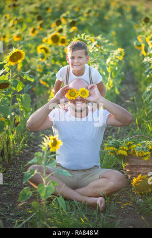 Papà con figlio abbracciando in un campo di girasoli. Figlio abbraccia il Padre in un campo di girasoli Foto Stock