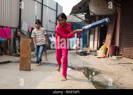 Mumbai, Maharashtra / India - 12 dicembre 2017: bambini che giocano i cosiddetti 'gully cricket' in una piccola strada in una delle baraccopoli di Mumbai. Foto Stock