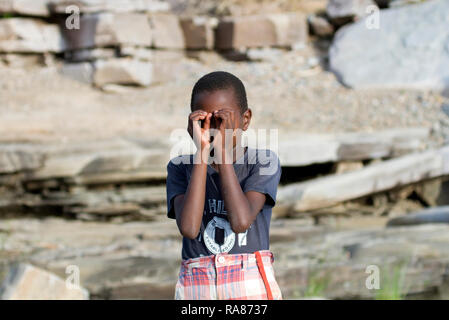 Ragazzo che agisce come egli è in possesso di un binocolo al villaggio Masai. Foto Stock