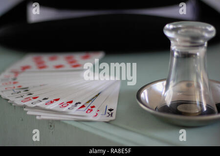 Attrezzatura di un mago. Schede, vetro, monete, tubo da stufa hat su un dipinto di cassa di legno. Foto Stock
