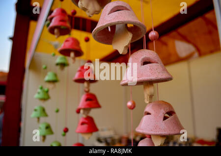 Colorato scacciapensieri nella forma di una campana del tempio fatto di argilla appesa al di fuori di una casa, il centro esposizioni, il negozio a Delhi Haat, Delhi, India Foto Stock