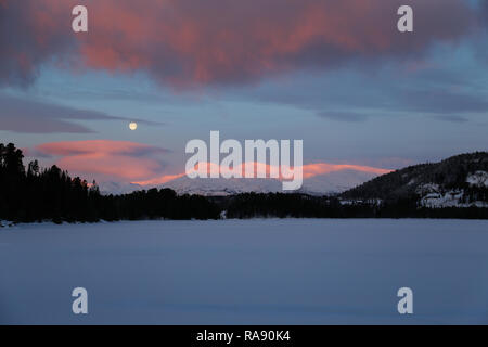 Luna in alba cielo sopra le montagne nevose Foto Stock