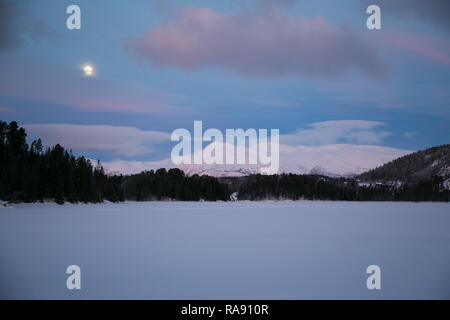 Luna in alba cielo sopra le montagne nevose Foto Stock