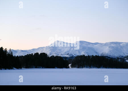 Vista la mattina di montagne innevate a ridosso del lago Foto Stock