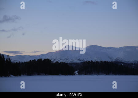 Vista della coperta di neve il lago con le montagne Foto Stock