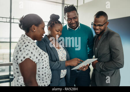 Il Team di business africana persone in piedi e si discute, utilizzando una compressa Foto Stock
