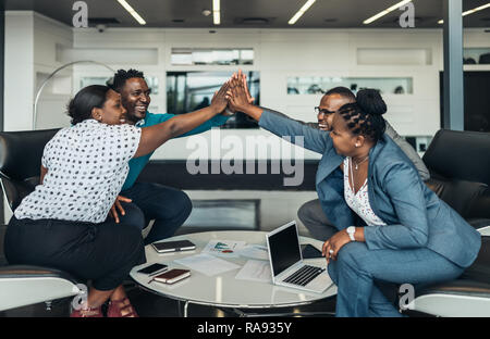 Cordiale successo tutti africani team aziendale dare alta cinque insieme in ufficio, eccitati felice dipendenti celebrando la vittoria aziendale, lavoratore africano Foto Stock