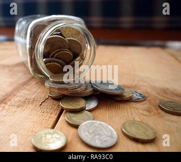 Prendendo delle monete dal vaso di risparmio Foto Stock
