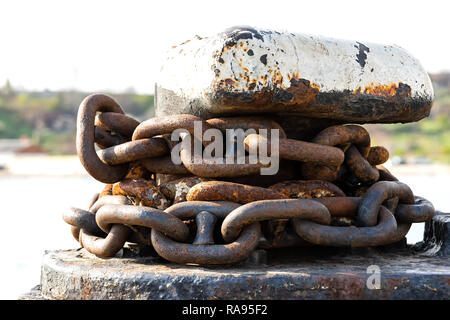 Rusty catena di ancoraggio intorno al posto barca bollard Foto Stock