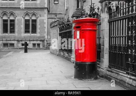 Il tradizionale britannico rosso casella postale a Londra in piedi sulla strada. Isolato in una foto in bianco e nero. Foto Stock