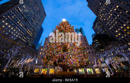 L'albero di Natale al Rockefeller Center circondato dagli angeli, turisti, visitatori e gli edifici. Foto Stock