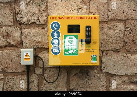 Un defibrillatore per uso pubblico montato esternamente su di un muro di pietra, Foto Stock